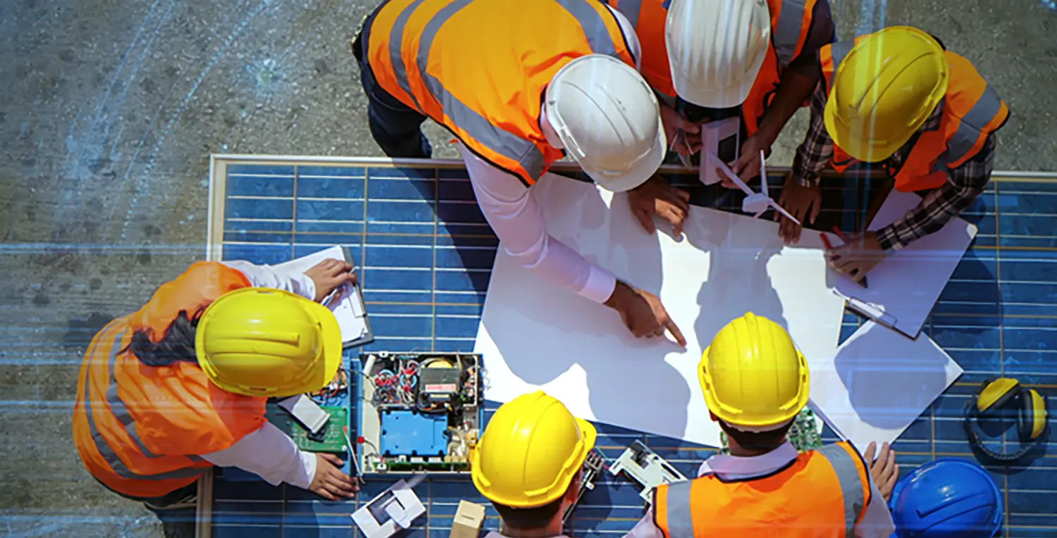 Engineers reviewing plans laid across a solar panel