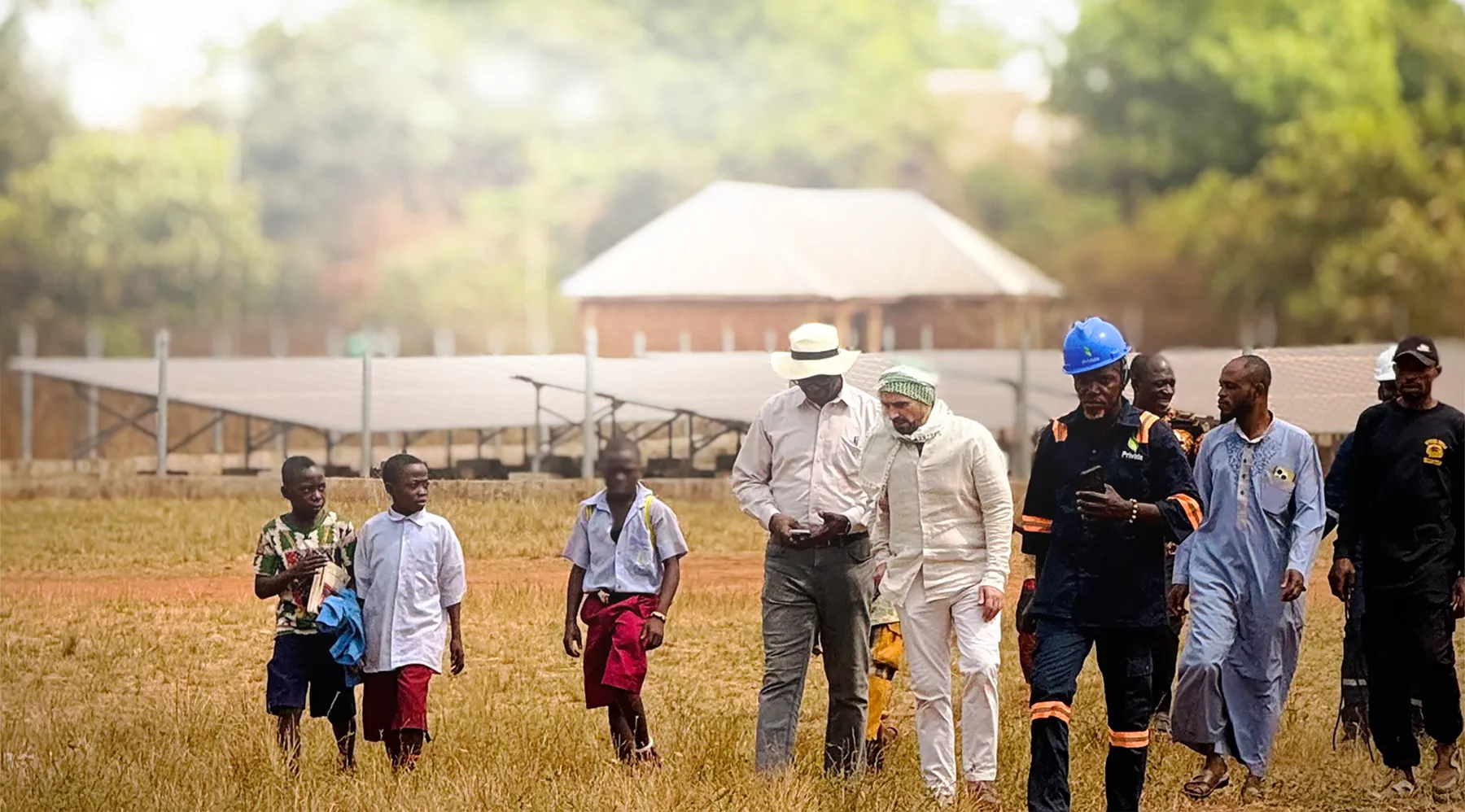 Saba and PriVida representatives walking with community members beside a solar array in Nigeria